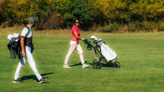 Pareja de estilo de vida de golf caminando en el campo de golf disfrutando de un hermoso día de otoño