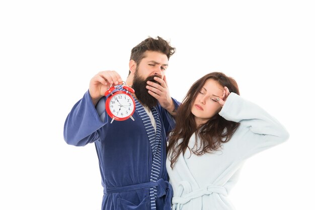 Pareja de familia cansada. hombre y mujer insomnes en bata de baño. despertar por la mañana. Alarma matutina. pareja sostenga el despertador. Trastornos del sueño. Somnoliento y débil por la mañana. puntualidad y disciplina.