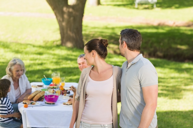 Pareja con familia cenando en la mesa al aire libre