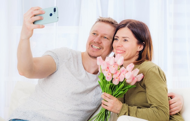 Pareja de familia tomando selfie con ramo de flores en el teléfono móvil