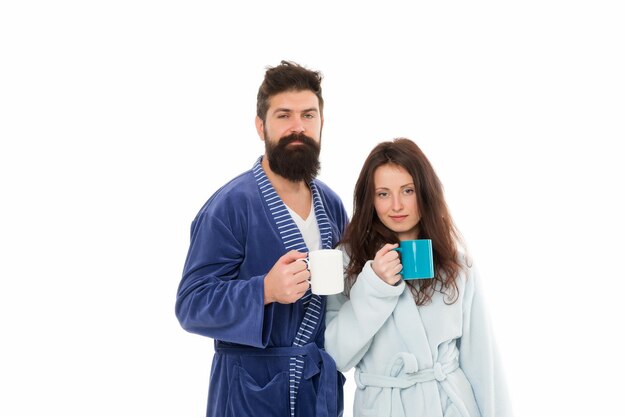 Pareja familiar bebe té en bata de baño pareja enamorada buenos días café hombre y mujer bebiendo leche de taza hipster barbudo con chica aislada en blanco rutina de vida cotidiana Desayuno saludable