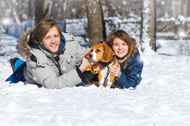 Pareja familiar con un cachorro beagle en el fondo de un paisaje invernal