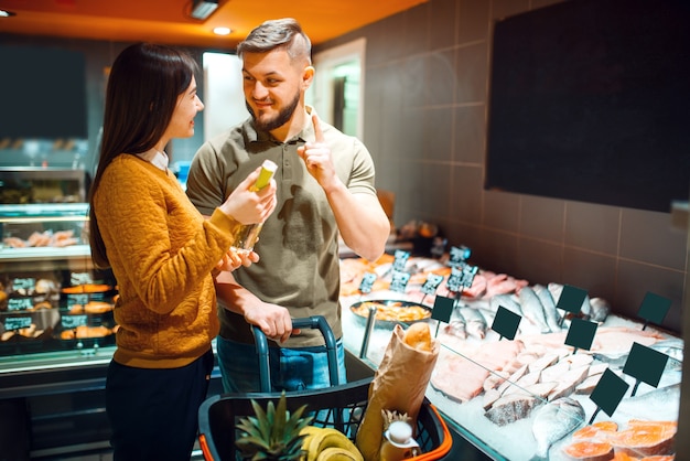 Pareja familiar eligiendo aceite para cocinar pescado en la tienda de comestibles