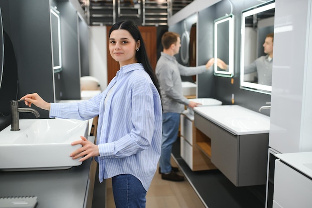 Pareja familiar joven eligiendo lavabo en la tienda de accesorios de baño