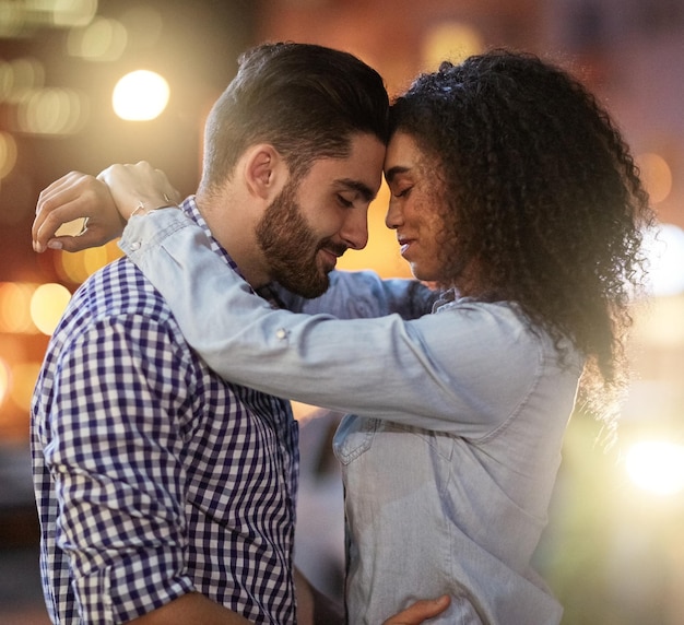 Pareja feliz y abrazar en la ciudad por la noche para el matrimonio aventura y fecha en vacaciones románticas Hombre mujer y bokeh con afecto en el amor por el compromiso lealtad y vacaciones de aniversario en California