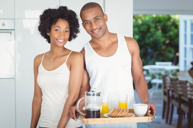 Pareja feliz con bandeja de desayuno en la cocina en casa