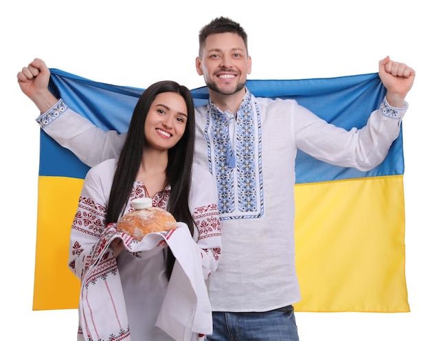 Foto pareja feliz con bandera de ucrania y korovai tradicional sobre fondo blanco