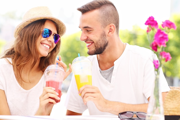 Una pareja feliz bebiendo batidos en un café exterior