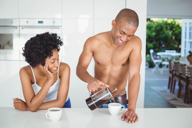 Pareja feliz bebiendo café en la cocina en casa