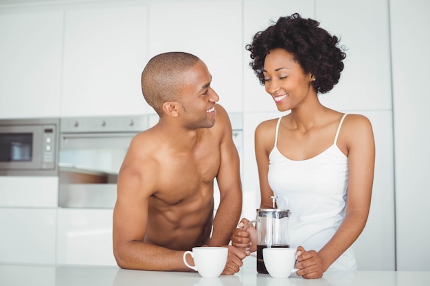 Pareja feliz bebiendo café en la cocina en casa