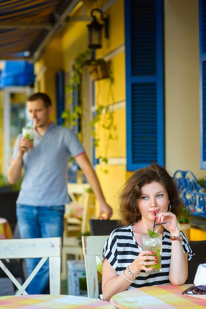 Pareja feliz bebiendo limonada o mojito en un café al aire libre.