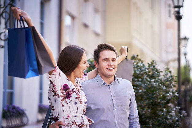 Pareja feliz con bolsas de la compra después de ir de compras en la ciudad sonriendo y abrazando.