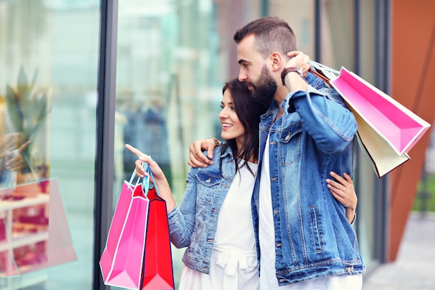 Pareja feliz con bolsas de la compra después de ir de compras en la ciudad