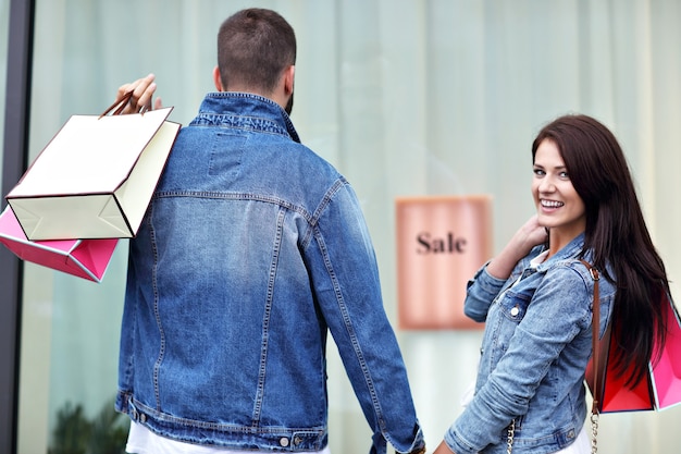 Pareja feliz con bolsas de la compra después de ir de compras en la ciudad