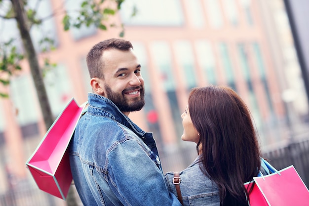 Pareja feliz con bolsas de la compra después de ir de compras en la ciudad