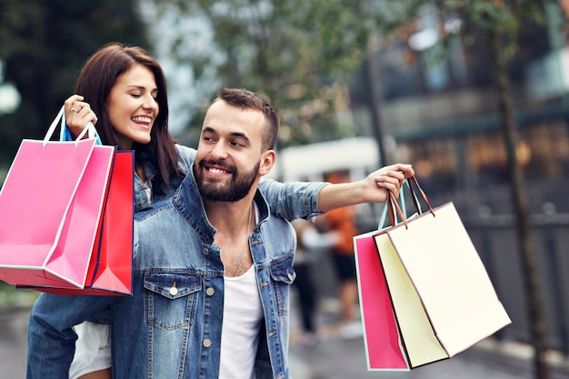 Pareja feliz con bolsas de la compra después de ir de compras en la ciudad