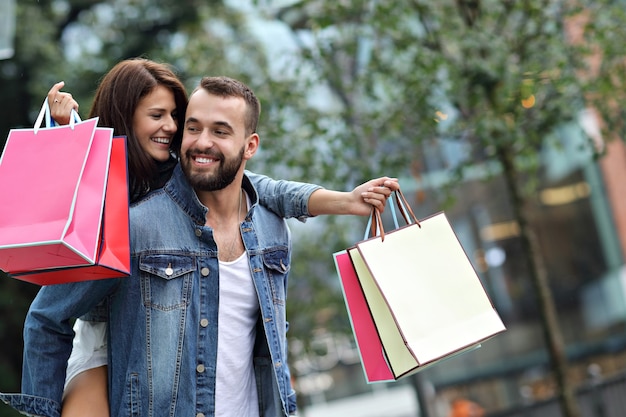 Foto pareja feliz con bolsas de la compra después de ir de compras en la ciudad