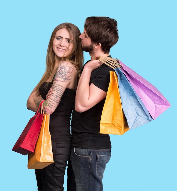 Pareja feliz con bolsas de la compra sobre un fondo azul.