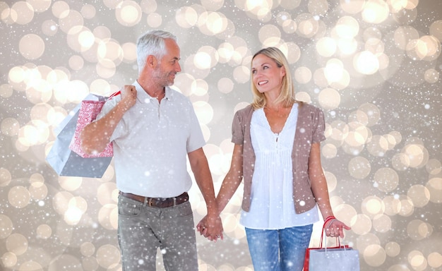 Pareja feliz con bolsas de compras contra el patrón de diseño de puntos brillantes de luz