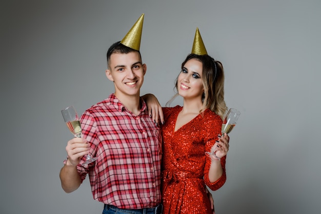 Pareja feliz con botella de champán y copas sobre gris