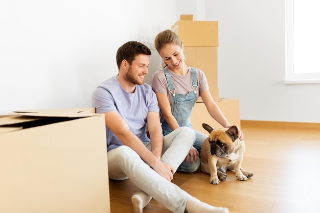 pareja feliz con cajas y perro moviéndose a un nuevo hogar