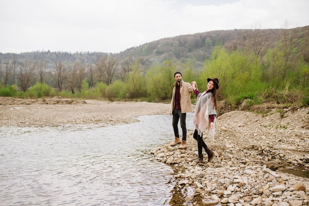 Pareja feliz caminando por el río en las montañas