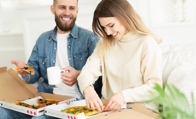 Pareja feliz comiendo pizza relajante el fin de semana en casa