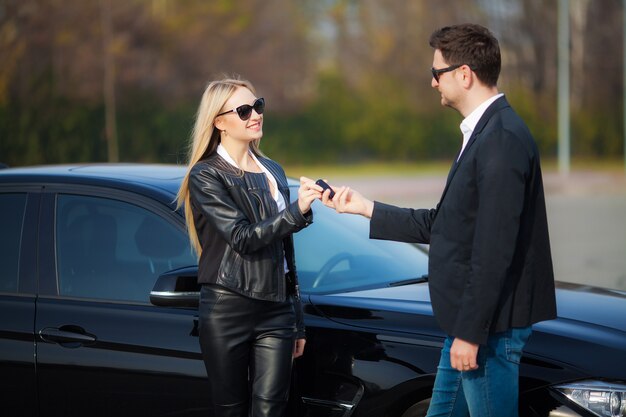 Pareja feliz compra nuevo coche negro moderno.