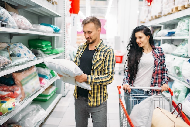 Pareja feliz comprando almohada en el supermercado