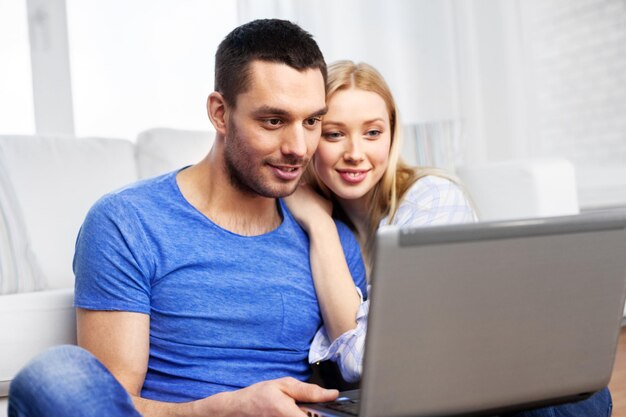 Foto pareja feliz con una computadora portátil en casa