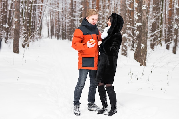 Pareja feliz consultando un teléfono inteligente en invierno en la calle