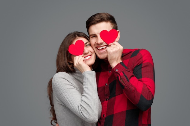 Foto pareja feliz con corazones cerca de los ojos