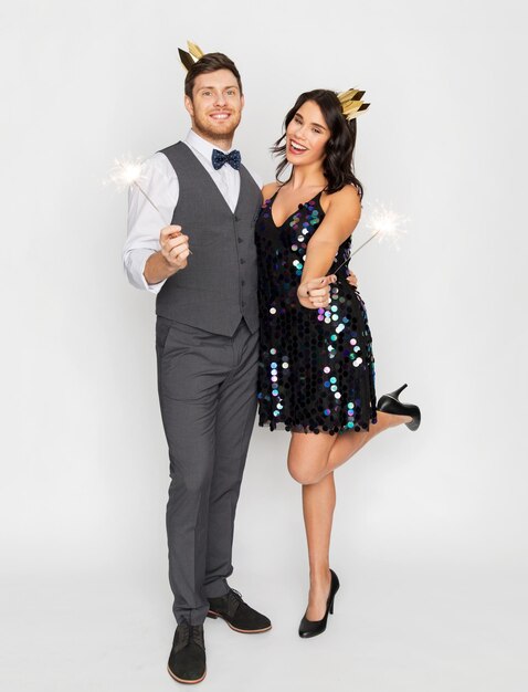 Foto pareja feliz con coronas y chispas en la fiesta