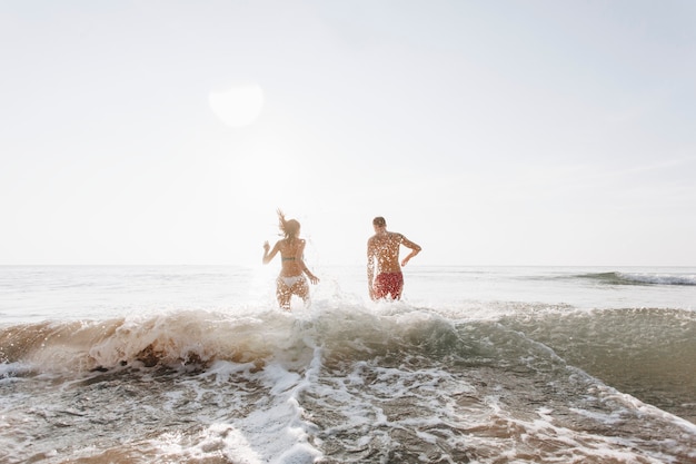 Pareja feliz corriendo en el agua