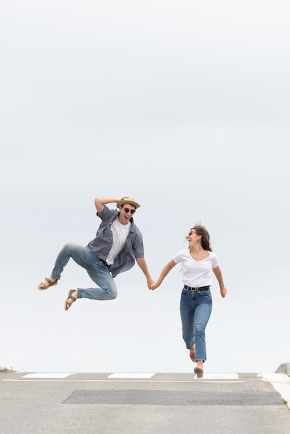 Pareja feliz corriendo y saltando en la carretera, celebrando el éxito. Concepto de felicidad con composición minimalista y espacio de copia.