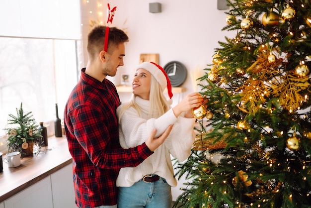 Pareja feliz decorando el árbol de navidad en casa Sonriente hombre y mujer juntos Celebrando la Navidad