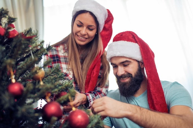 Pareja feliz decorando el árbol de Navidad en su casa