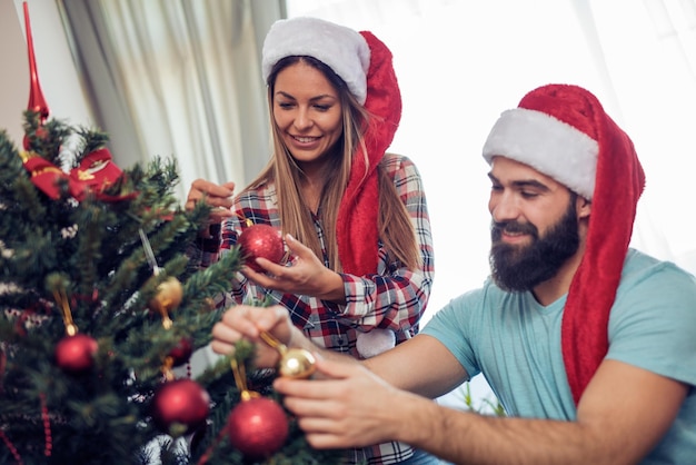 Pareja feliz decorando el árbol de Navidad en su casa