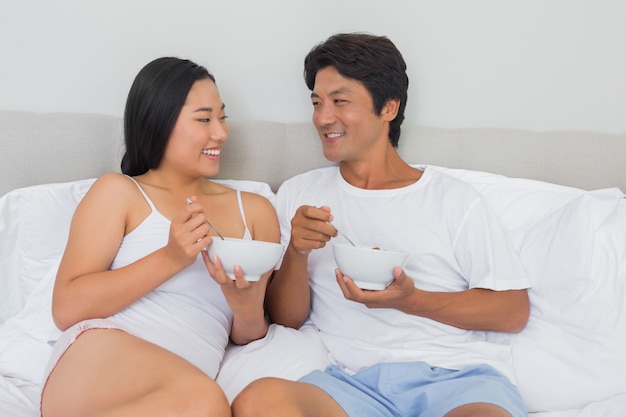 Pareja feliz desayunando en la cama