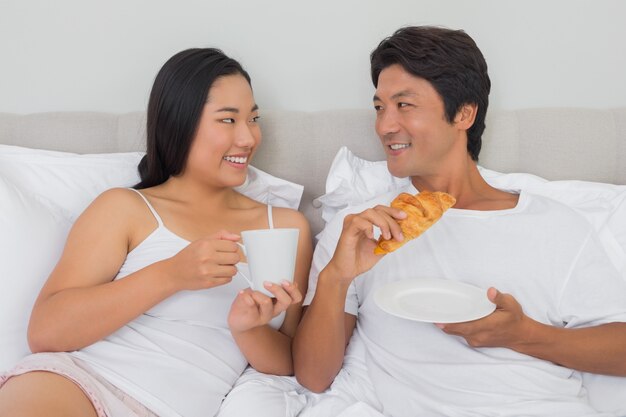 Pareja feliz desayunando en la cama