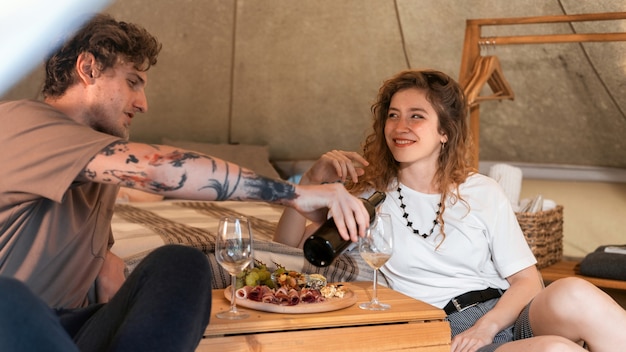 Una pareja feliz descansando en una carpa en el glamping Vino y comida