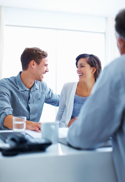 Pareja feliz discutiendo con asesor Retrato de pareja feliz riendo mientras discutiendo con asesor financiero