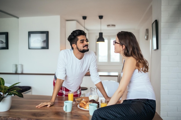 Pareja feliz disfrutando del desayuno en casa por la mañana