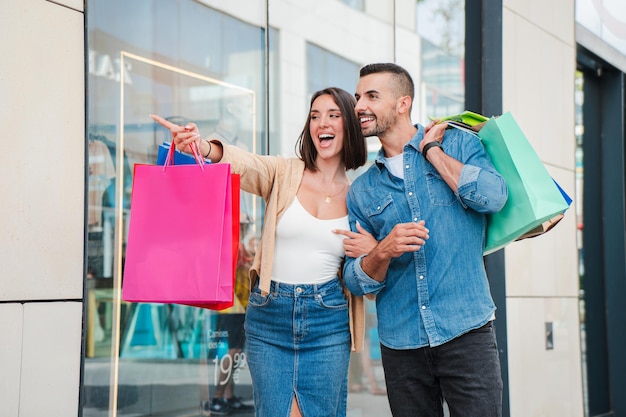 Pareja feliz disfrutando de un día de compras juntos viendo ventas minoristas promociones y descuentos en