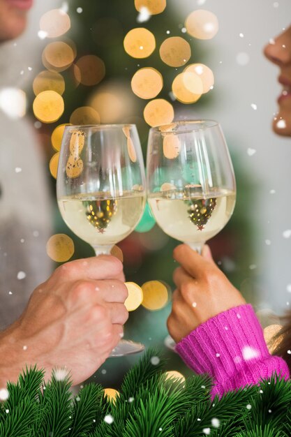 Foto pareja feliz disfrutando de un poco de vino contra ramas de abeto verde con nieve