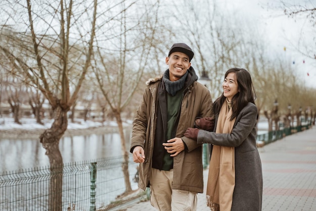 Foto una pareja feliz disfrutando de su tiempo juntos caminando cerca de un río en invierno