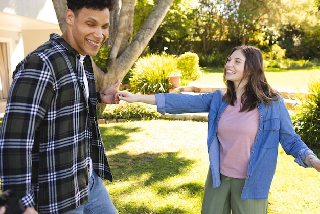 Una pareja feliz y diversa bailando en un jardín soleado.