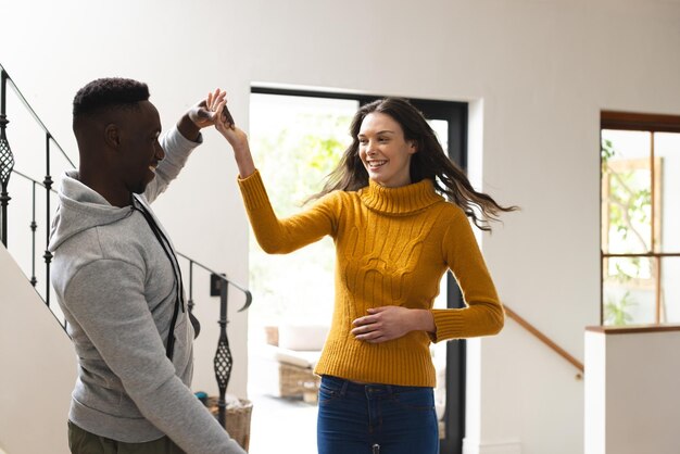 Foto una pareja feliz y diversa bailando en el pasillo de su casa.