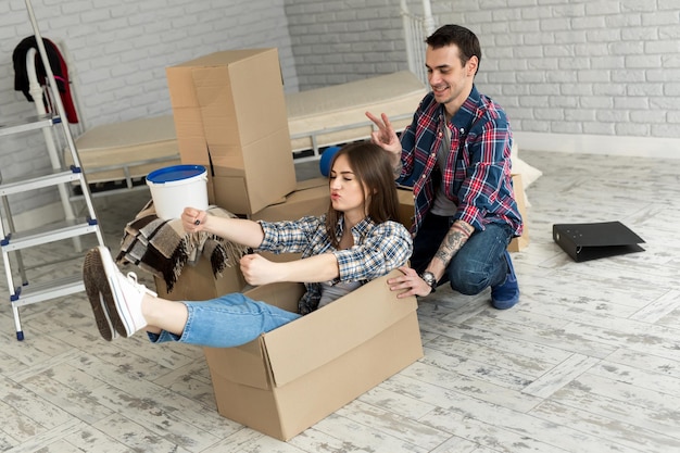 Pareja feliz divirtiéndose riendo mudándose a un nuevo hogar joven emocionada mujer montando