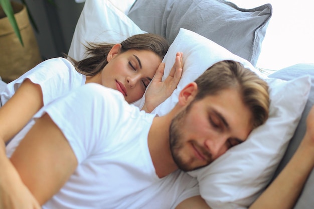 Pareja feliz durmiendo en una cama cómoda en casa